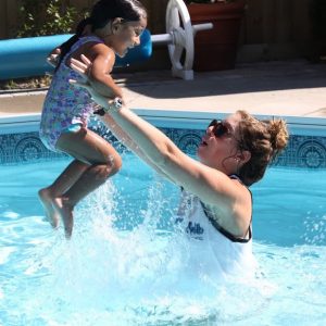 AquaMobile travelling swim instructor holding a little girl in the water at a pool