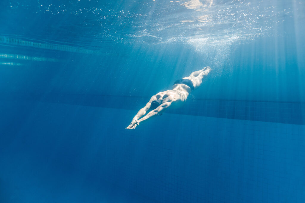 Male swimmer diving into a deep swimming pool